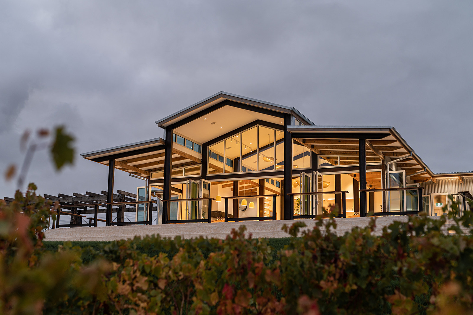 Hills Cellar Door at dusk, glowing timber pavilion above the vines