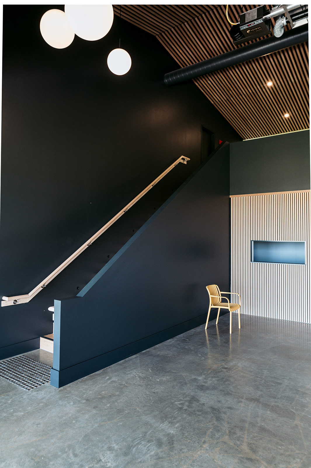 Dark timber stair rising past a slatted screen inside the studio
